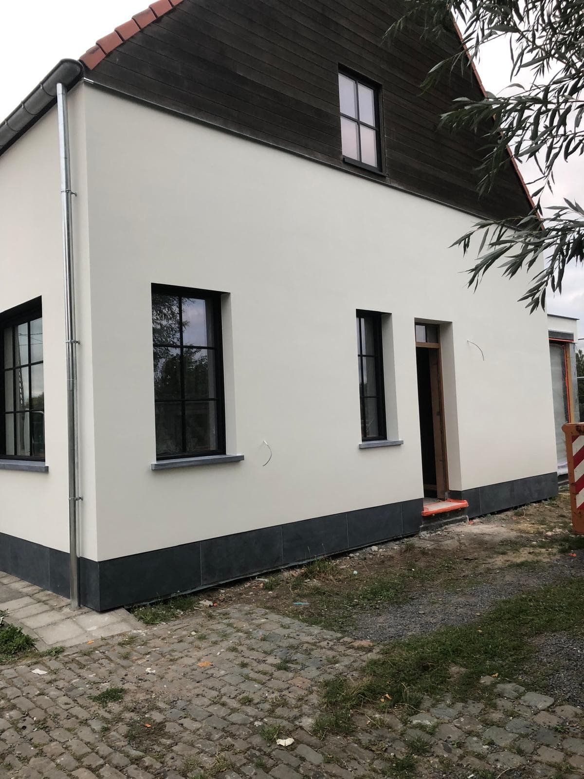 Crepi gevel met blauwsteen plint en houten topgevel